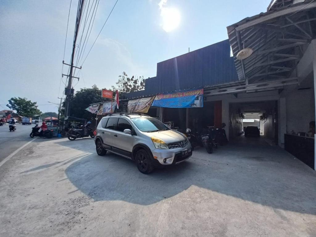 een witte SUV geparkeerd voor een gebouw bij OYO 93962 Jm Guest House in Pundong