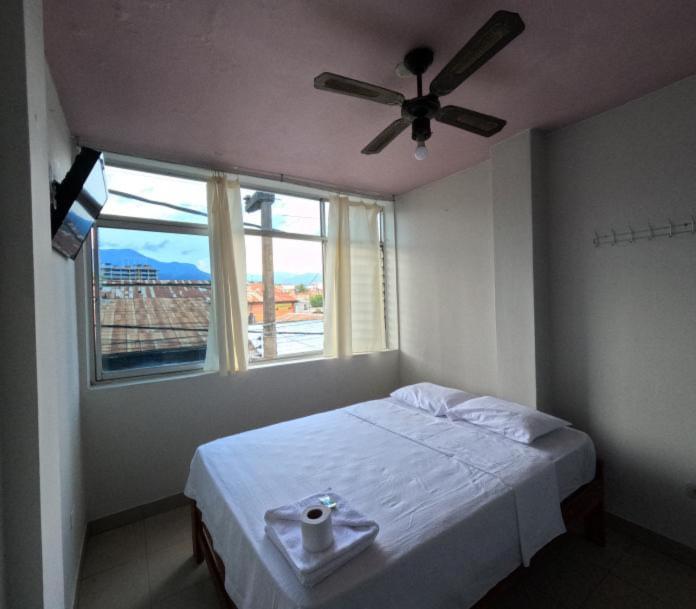 een slaapkamer met een bed, een plafondventilator en een raam bij Hospedaje Koral in Tarapoto