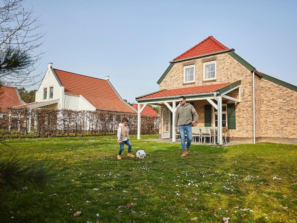 a man and a child playing with a soccer ball at Spledid villa with sauna and whirlpool in Limburg in Roggel