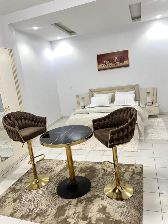 a bedroom with a bed and two chairs and a table at Keur GORA, Sacré cœur 2 in Dakar
