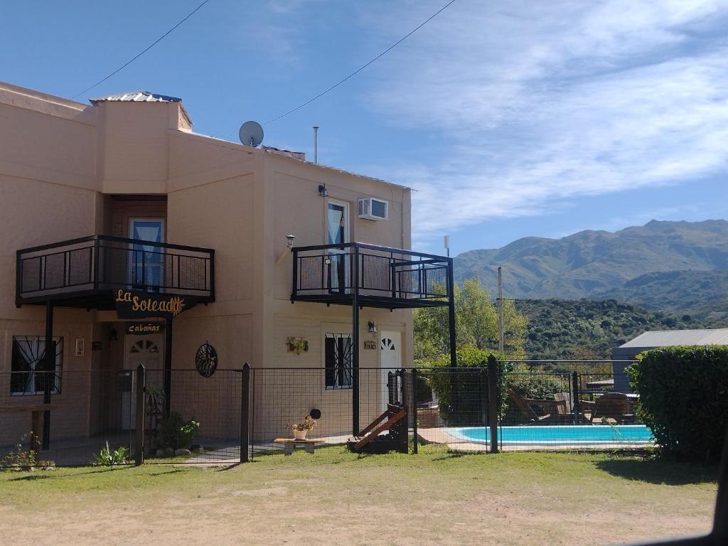 a building with a pool in front of a house at Cabañas La Soleada in Potrero de los Funes