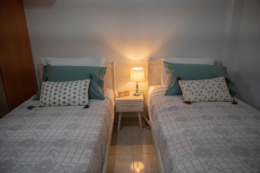 1 dormitorio con 2 camas y una lámpara en una mesa en Cloe Corfu Airport Apartment en Anemómylos