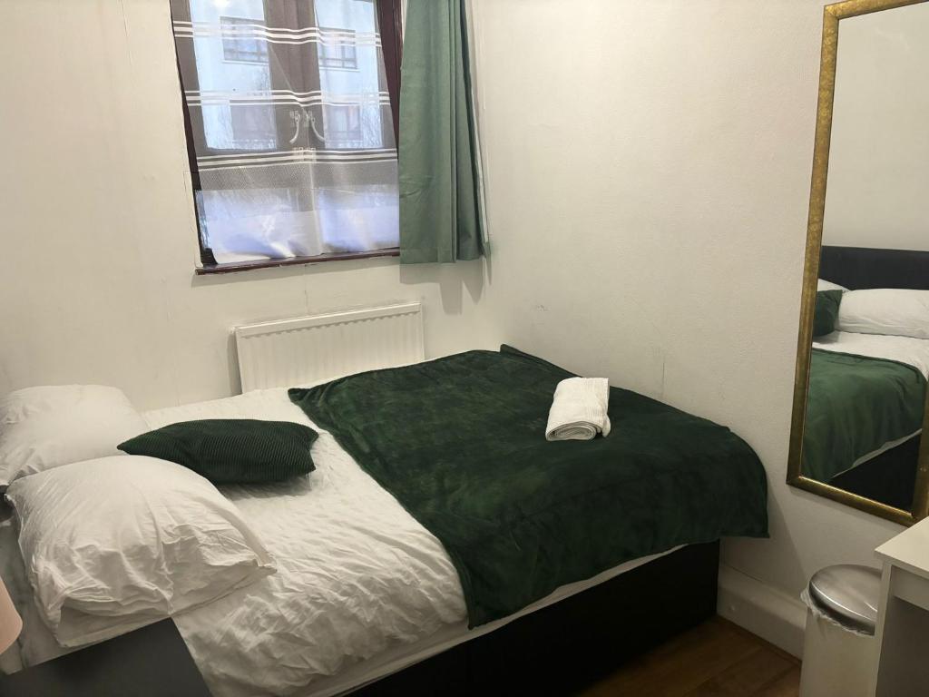 a bedroom with a bed with a green blanket and a mirror at Fleetway Private Rooms in Central London in London