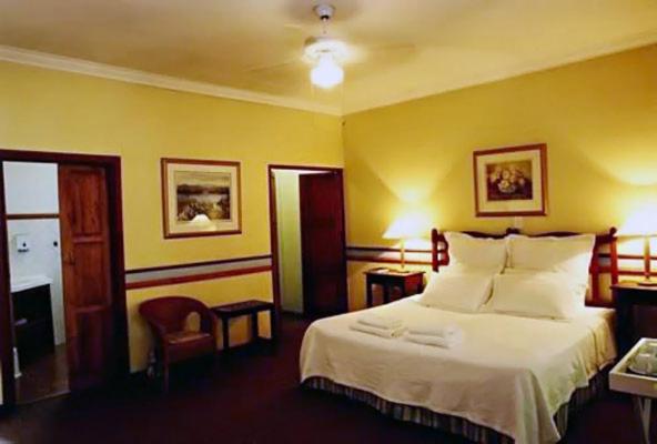 a bedroom with a large bed and yellow walls at Pumulani Lodge in Pretoria
