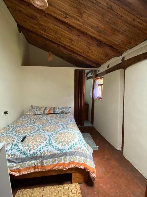 1 dormitorio con cama y techo de madera en Casita Hierbabuena en Ibarra