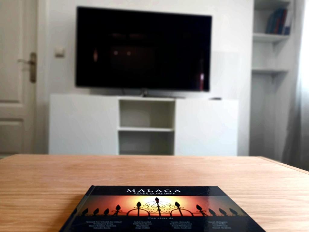 un libro sobre una mesa con TV en Apartamento vacacional Cuarteles, en Málaga