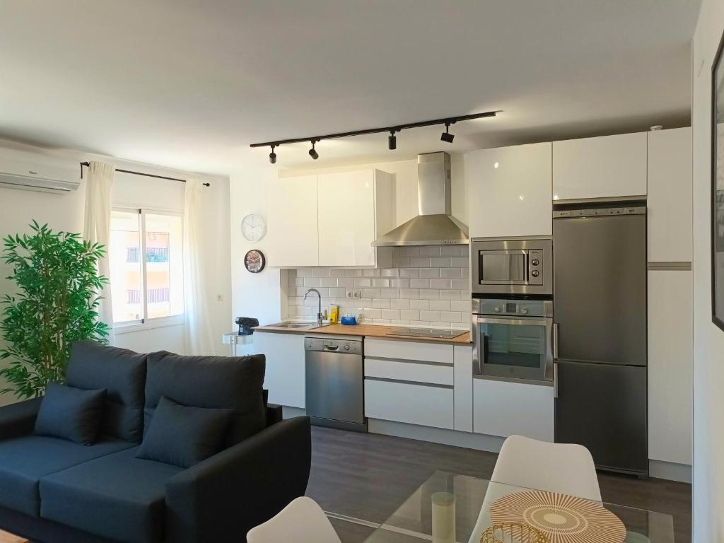 un salon avec un canapé bleu et une cuisine dans l'établissement Apartamento vacacional Cuarteles, à Malaga