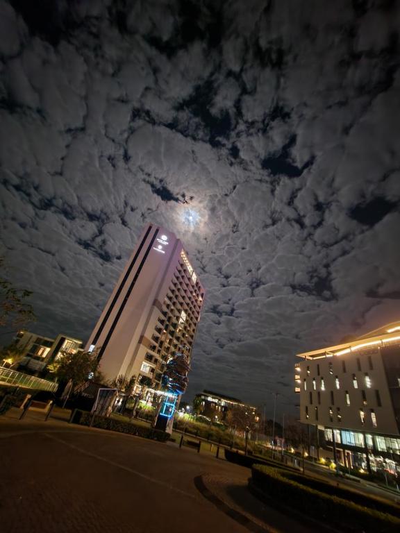 um edifício com a lua no céu à noite em 10th floor, Unit 1008, in The Capital Trilogy, overlooking Sun Time Square em Pretoria