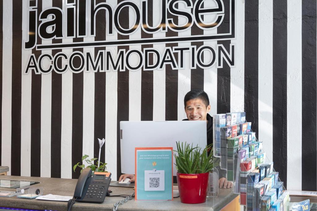 a man standing behind a table with a computer at Jailhouse Accommodation in Christchurch