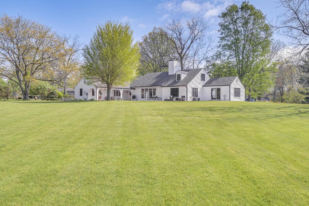 a large white house with a large grass field at Knoxville Area Getaway on 22 Acres with Pond Access! in Galesburg