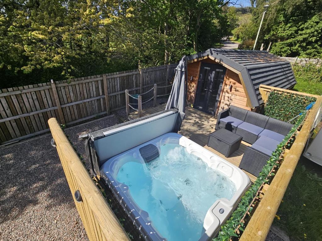 una gran bañera de hidromasaje en un patio trasero con una casa para perros en Morvan Pod & Hot tub en Fort William