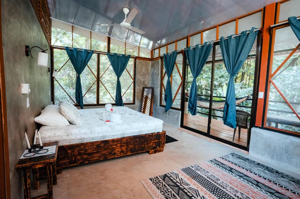 1 dormitorio con 1 cama en una habitación con ventanas en Kinkajoungalows - Amaya Family, Drake Bay, Osa Peninsula, en San Pedrillo