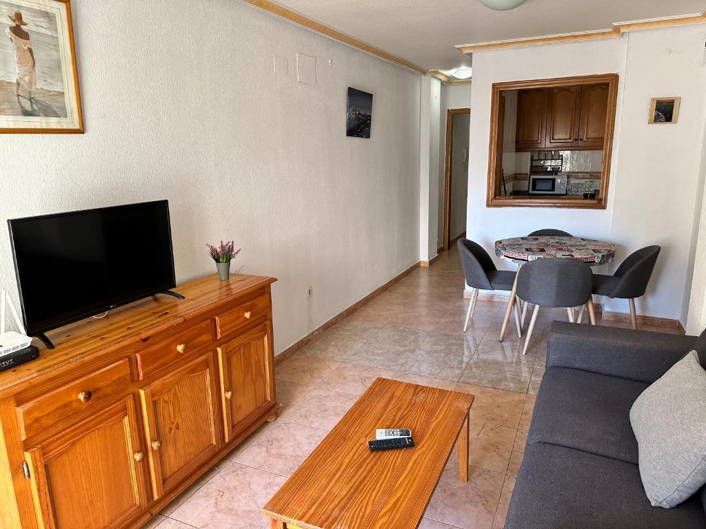 sala de estar con sofá y TV de pantalla plana en Homely Apartments Alcatri, en Torrevieja