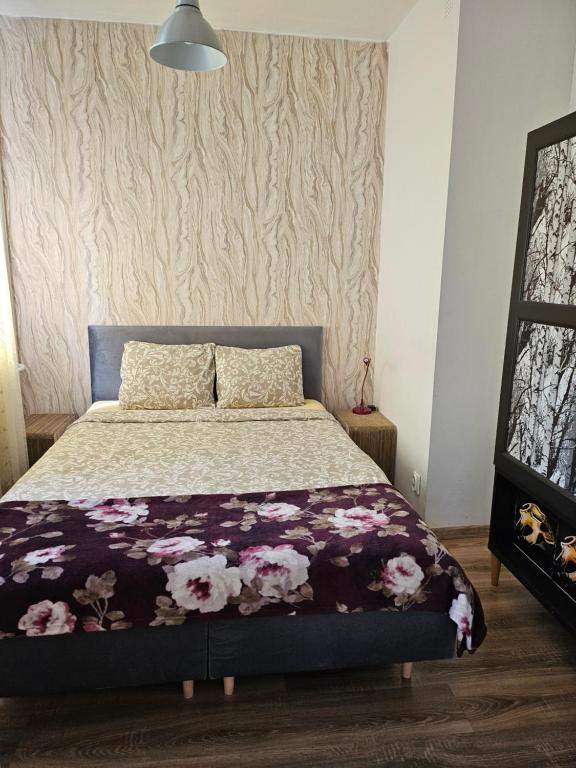 a bedroom with a bed with flowers on it at Apartament Góralska in Gdańsk