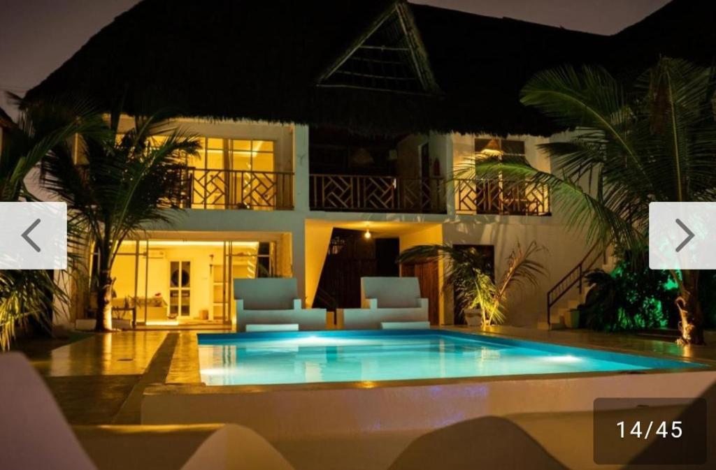 a swimming pool in front of a house at night at Ayras Hotel Zanzibar in Paje