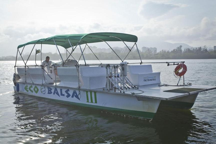 a white boat with a green canopy on the water at Conforto no Coração da Barra in Rio de Janeiro