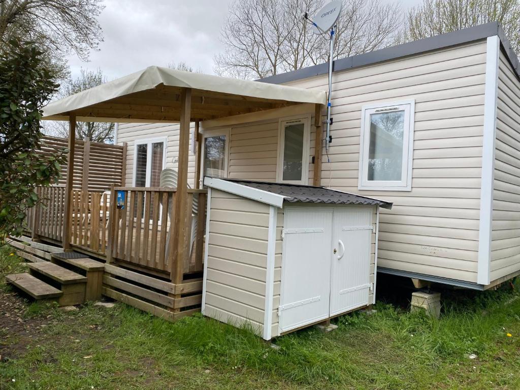 een klein wit huis met een dak en een veranda bij Les Catalpas *** charmant mobilhome à louer in Saint-Georges-de-Didonne