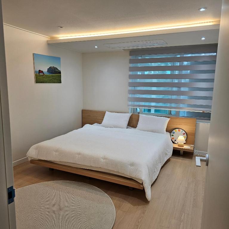 una camera con un grande letto e una finestra di Caty House Hyeopjae a Jeju