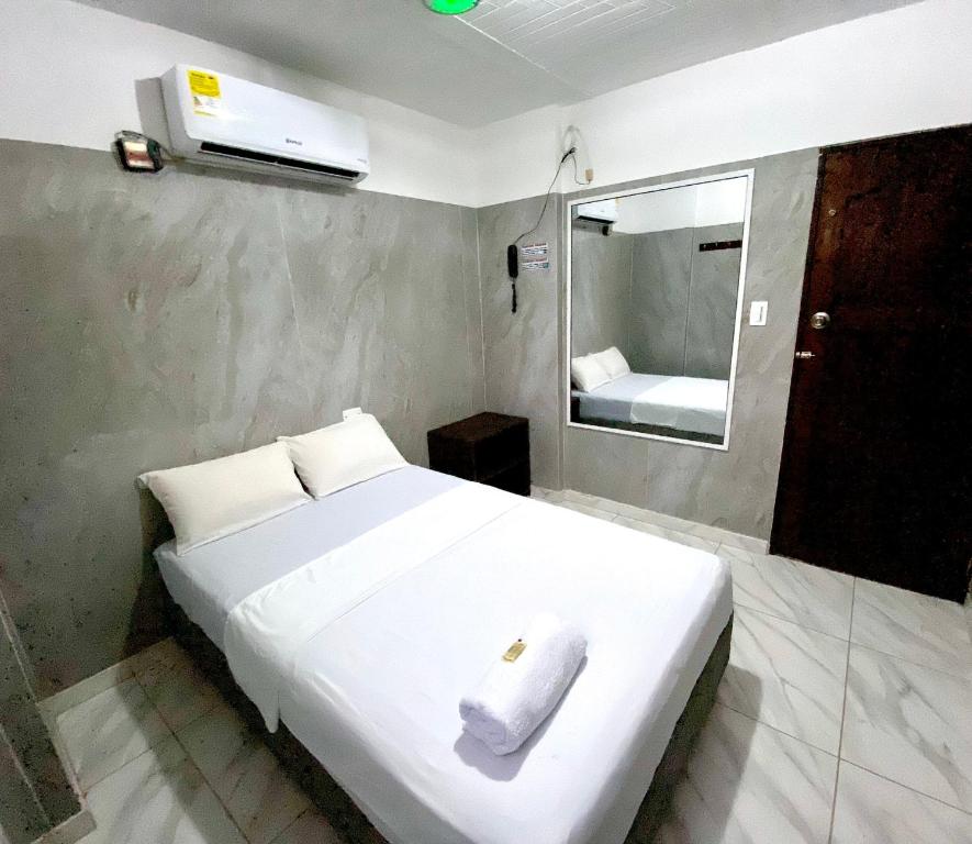 una camera da letto con un letto bianco e un asciugamano sopra di Hotel Rancho Grande a Barranquilla