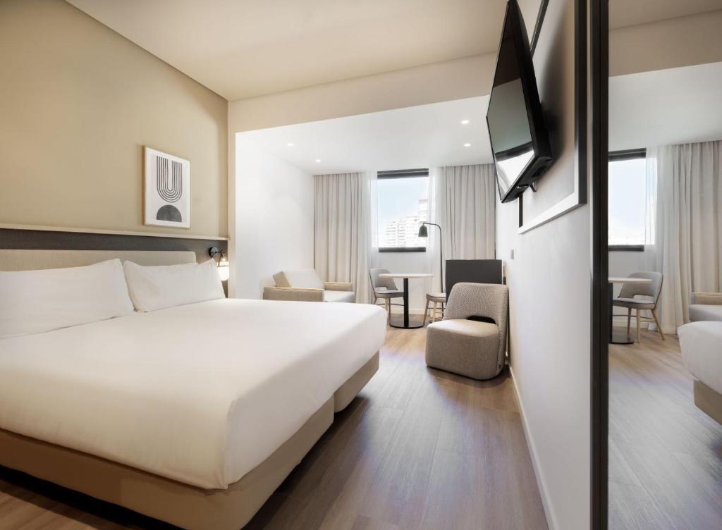 ein Hotelzimmer mit einem weißen Bett und einem TV in der Unterkunft Hotel Málaga Alameda Centro Affiliated by Meliá in Málaga