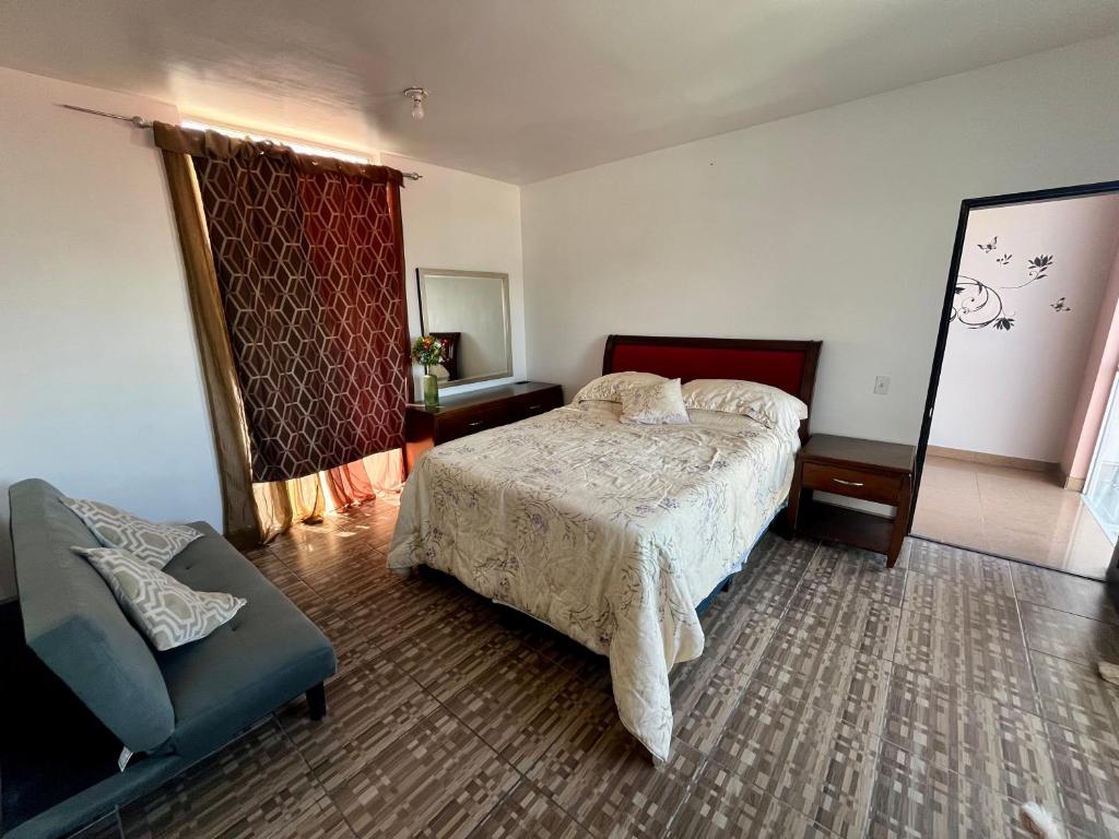 a bedroom with a bed and a chair and a window at Casa en Chapultepec California in Tijuana