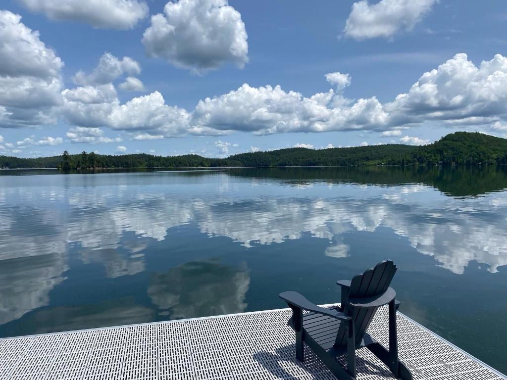 a chair sitting on the edge of a lake at Pimishka Chalet-Cottage-Studios in Bouchette