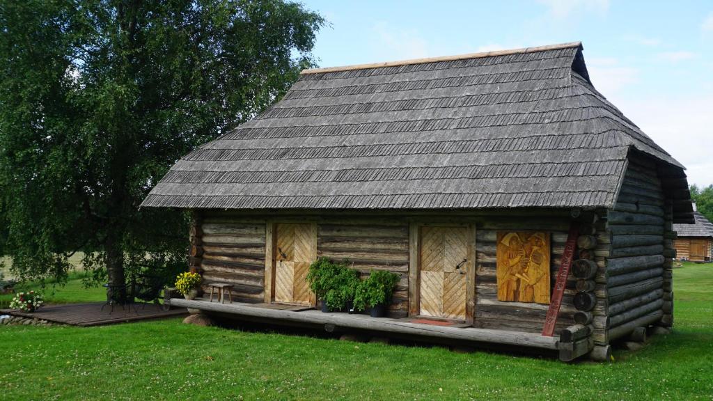 a log cabin with a gray roof on a green field at Hubane seto talu ait in Leimani