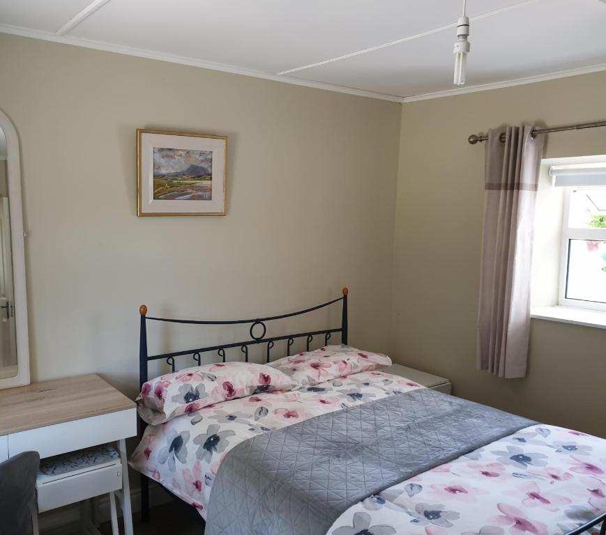 a bedroom with a bed and a desk and a window at Dungloe Lakeside Lodging in Dungloe