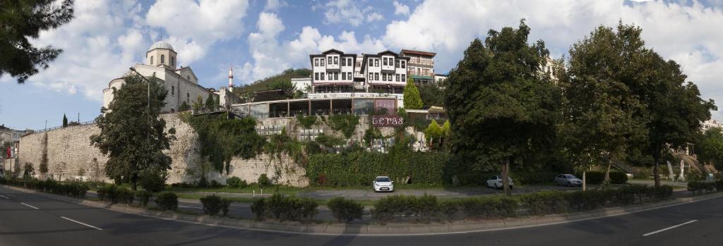 a building on top of a stone wall with cars parked on the street at İkizevler Hotel in Ordu