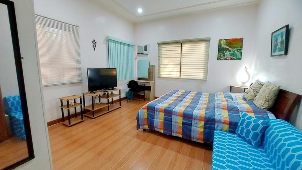 a bedroom with a bed and a flat screen tv at Liturs house in Bacolod