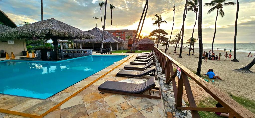 una piscina junto a una playa con palmeras en Peco Paradise Cumbuco Ap119, en Cumbuco