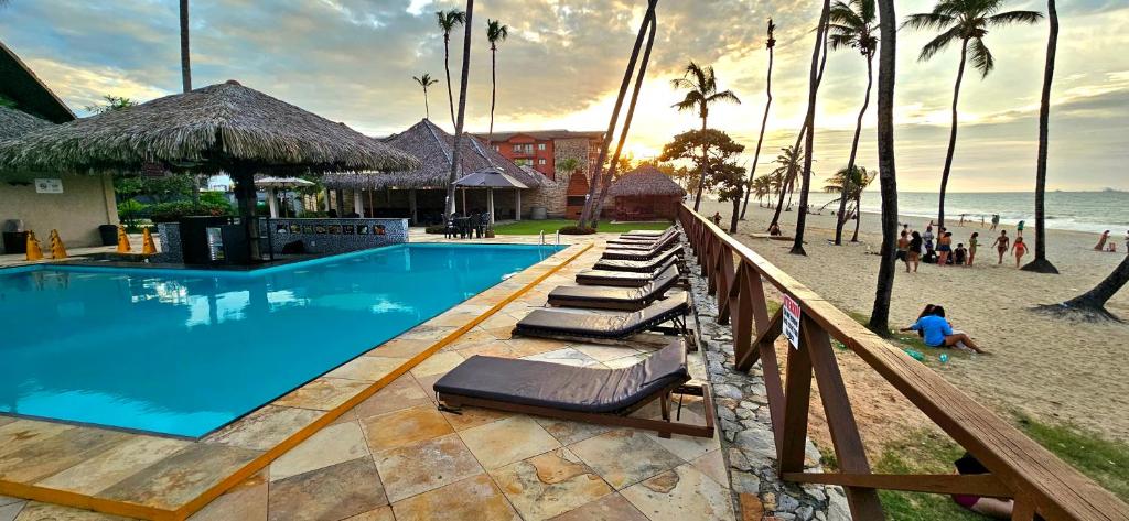 a swimming pool next to a beach with palm trees at Peco Paradise Cumbuco Ap119 in Cumbuco