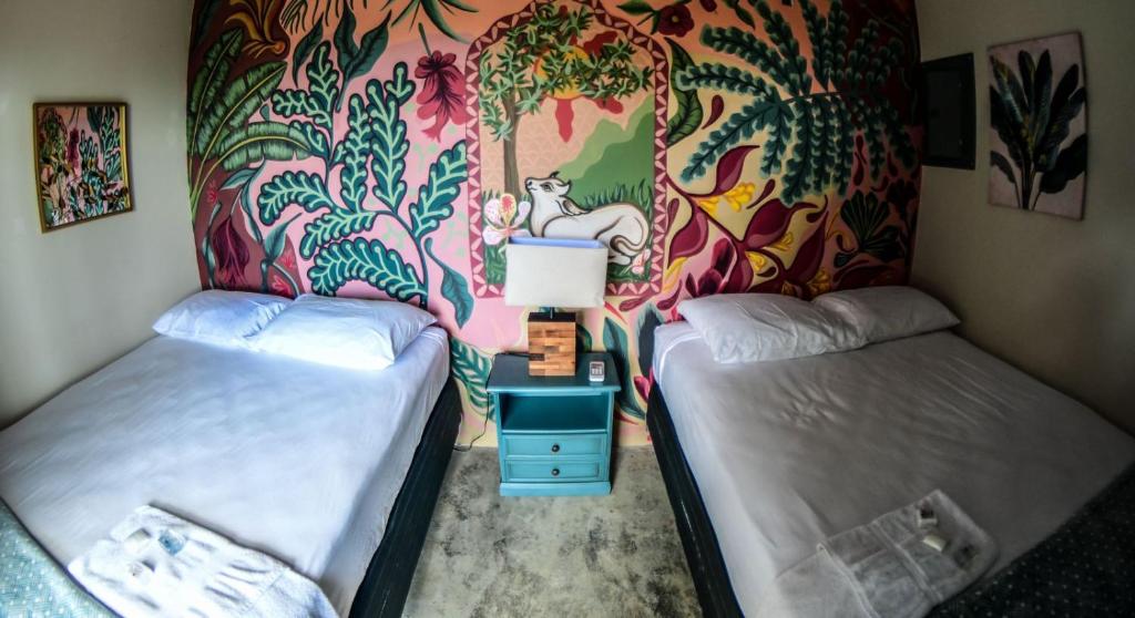 dwa łóżka w pokoju z kolorową ścianą w obiekcie Sunset Hut Hostel w mieście Omoa