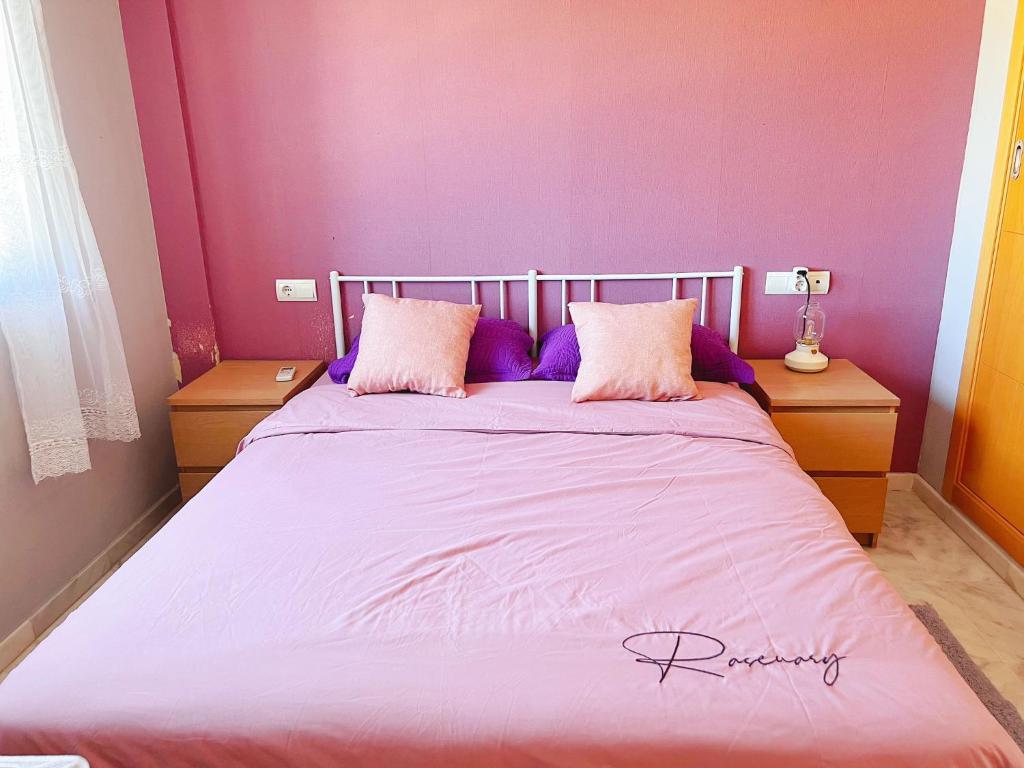 Una cama con almohadas moradas en un dormitorio en Habitaciones compartido Huelva, en Huelva
