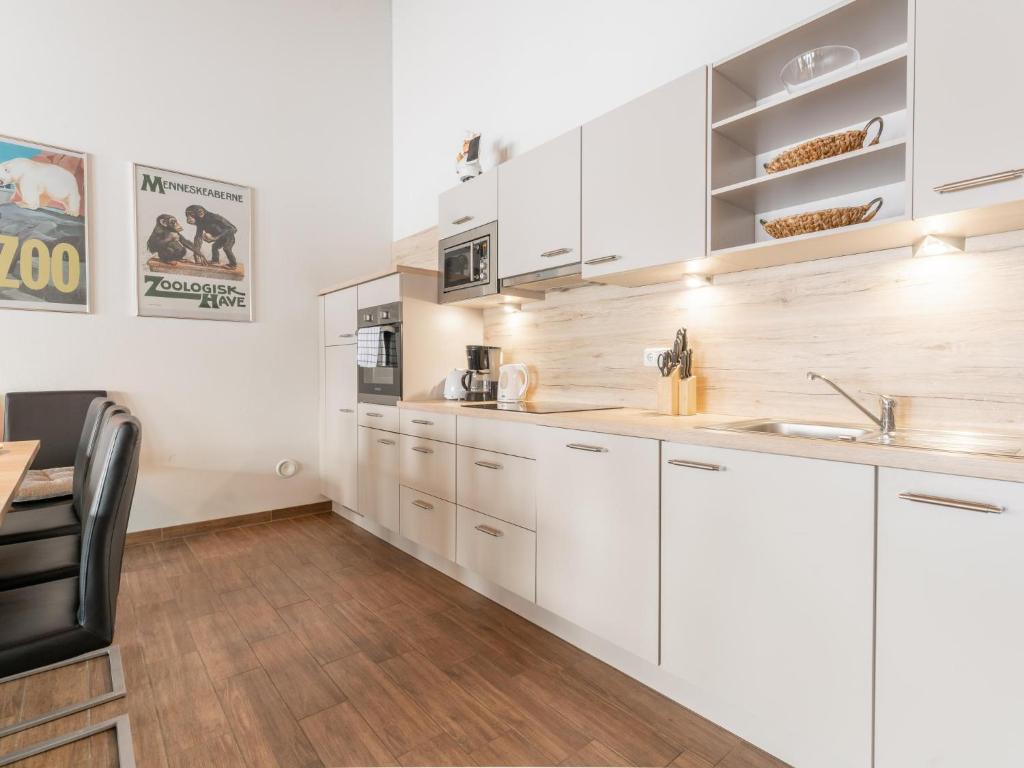 a kitchen with white cabinets and a wooden floor at Emma Top 3 XL in Dienten am Hochkönig