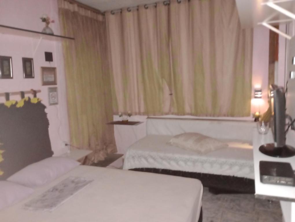 a bedroom with two beds and a window with curtains at Pousada Lua Nua in Niterói