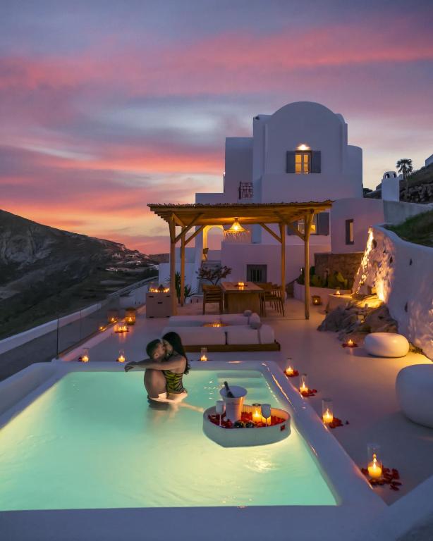 a couple bathing in a pool at sunset at Bluewhite Suites & Villa Santorini in Pyrgos