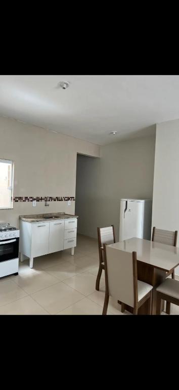 een keuken met een tafel, stoelen en een koelkast bij Apto Nossa Senhora Aparecida in Aparecida