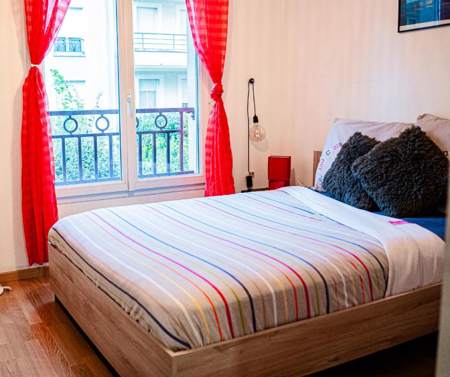 a bedroom with a bed and a window with red curtains at Heyzie in Pontault-Combault