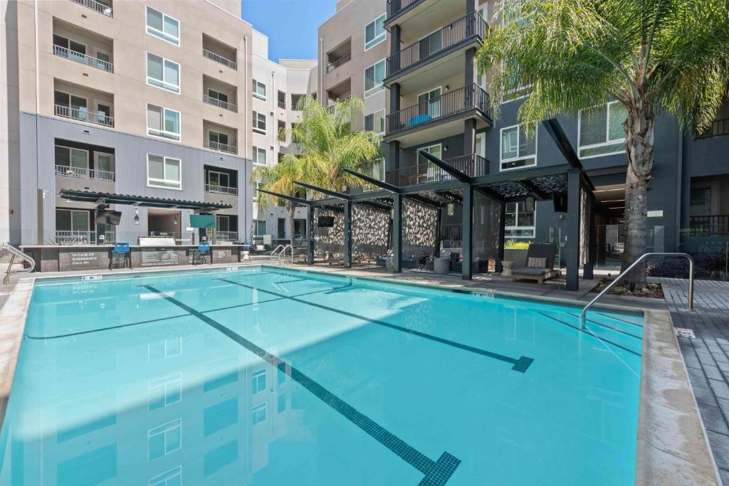 a large swimming pool with palm trees and buildings at Cozy Glendale Apartment in Los Angeles