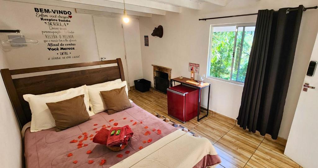 a bedroom with a bed and a fireplace and a window at Pousada Villa Bergamin in Monte Verde