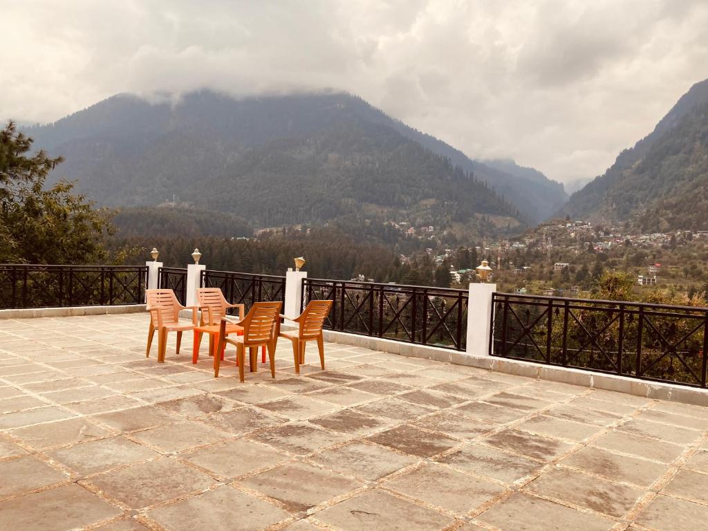 una mesa y sillas en un patio con vistas a las montañas en Sandeep Restro & Cafe, en Rajkot