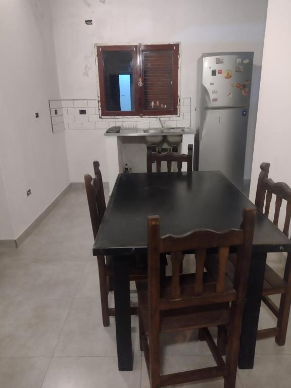 eine Küche mit einem Tisch und Stühlen sowie einem Kühlschrank in der Unterkunft Dpto Lgolf club cerca de Estadio único in Santiago del Estero