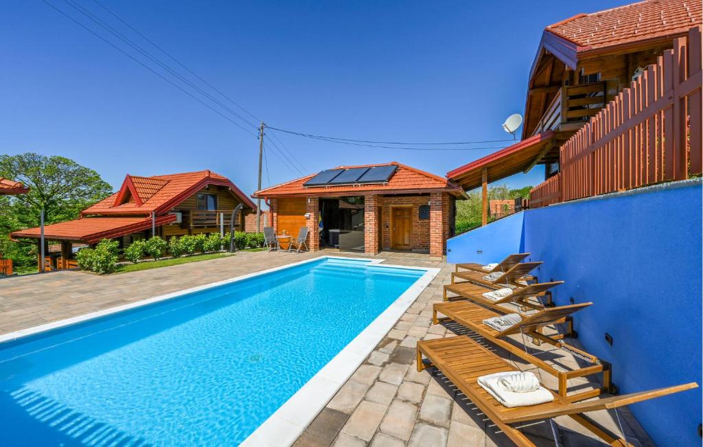 a swimming pool with chairs next to a house at Beautiful Home In Vinogradi Ludbreski With Heated Swimming Pool in Ludbreg
