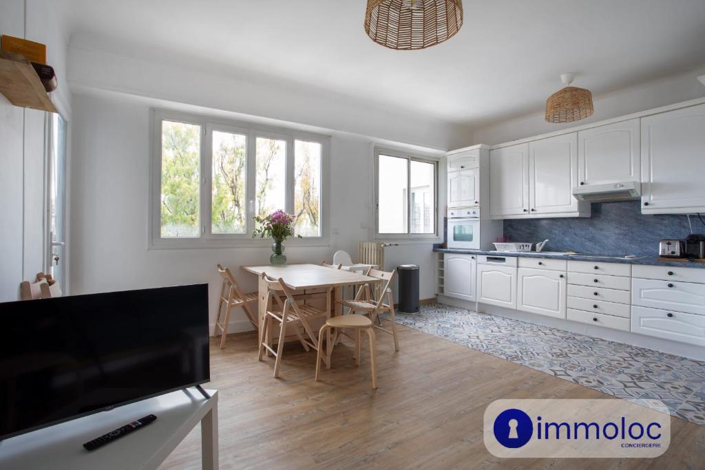 une cuisine avec des armoires blanches et une table avec des chaises dans l'établissement Apartment with air conditioning Libération, à Nice