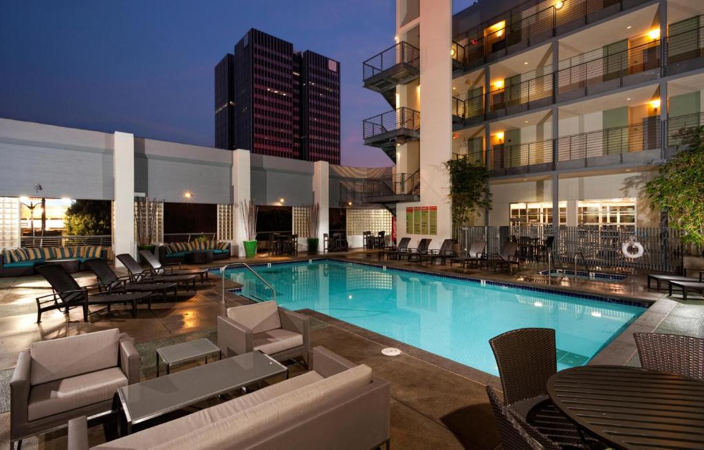 a swimming pool with chairs and tables and a building at Luxury Hollywood Apartment in Los Angeles