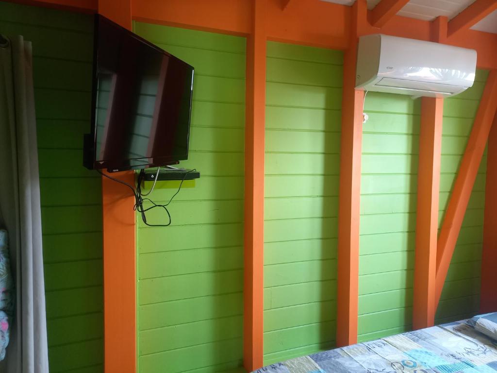 Elle est dotée d'un mur vert et d'une télévision à écran plat. dans l'établissement Fatou location, à Petit-Bourg