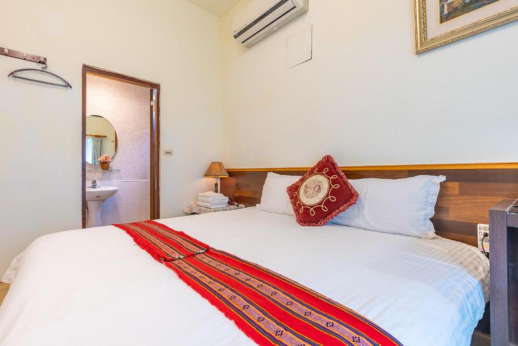 a bedroom with a bed with a red pillow on it at Yishin Garden B&amp;B in Pinghe