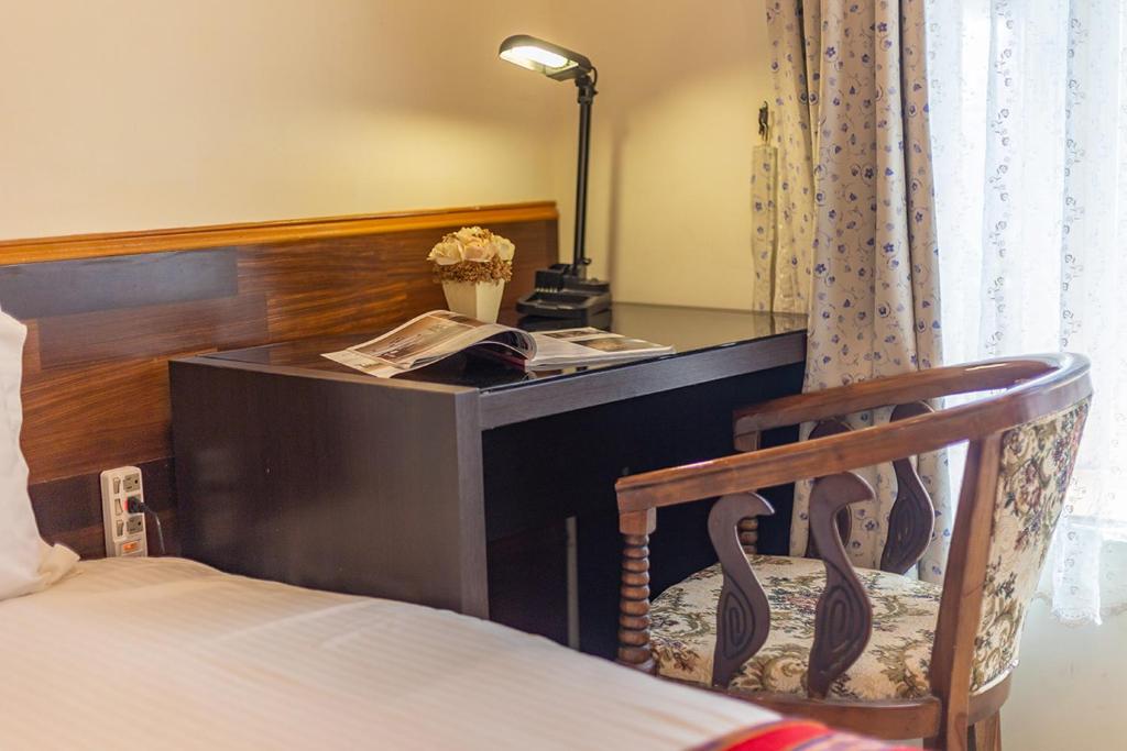 a desk with a lamp and a chair next to a bed at Yishin Garden B&amp;B in Pinghe