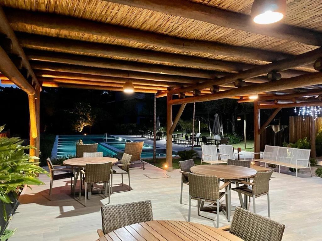 un patio con mesas y sillas y una piscina en Praia do Forte - COND ALTO DA ENSEADA - Casa 302 en Mata de Sao Joao